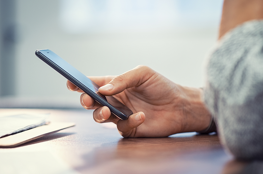 Closeup hand of woman using smartphone on wooden table